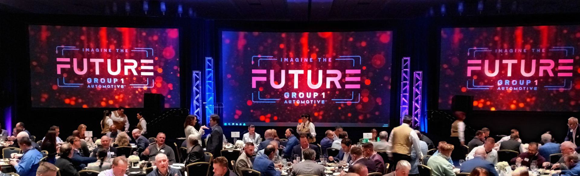 Group 1 Automotive 2024 annual meeting general session with three projection screens and lit truss towers at Disney's Yacht and Beach Club Resort, Orlando