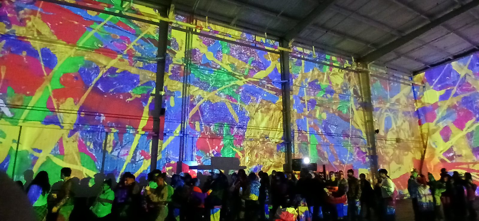 Large-scale interior projection mapping across the walls of a warehouse venue during a crowded activation, produced by NAVP