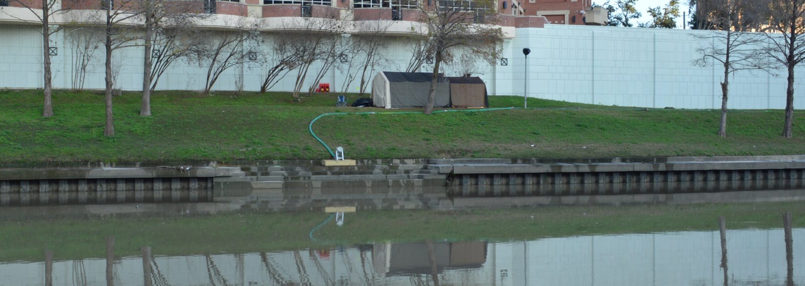 Daytime view of an outdoor water-screen projection site, with the projector shelter and water screen line on the bank, set up by NAVP