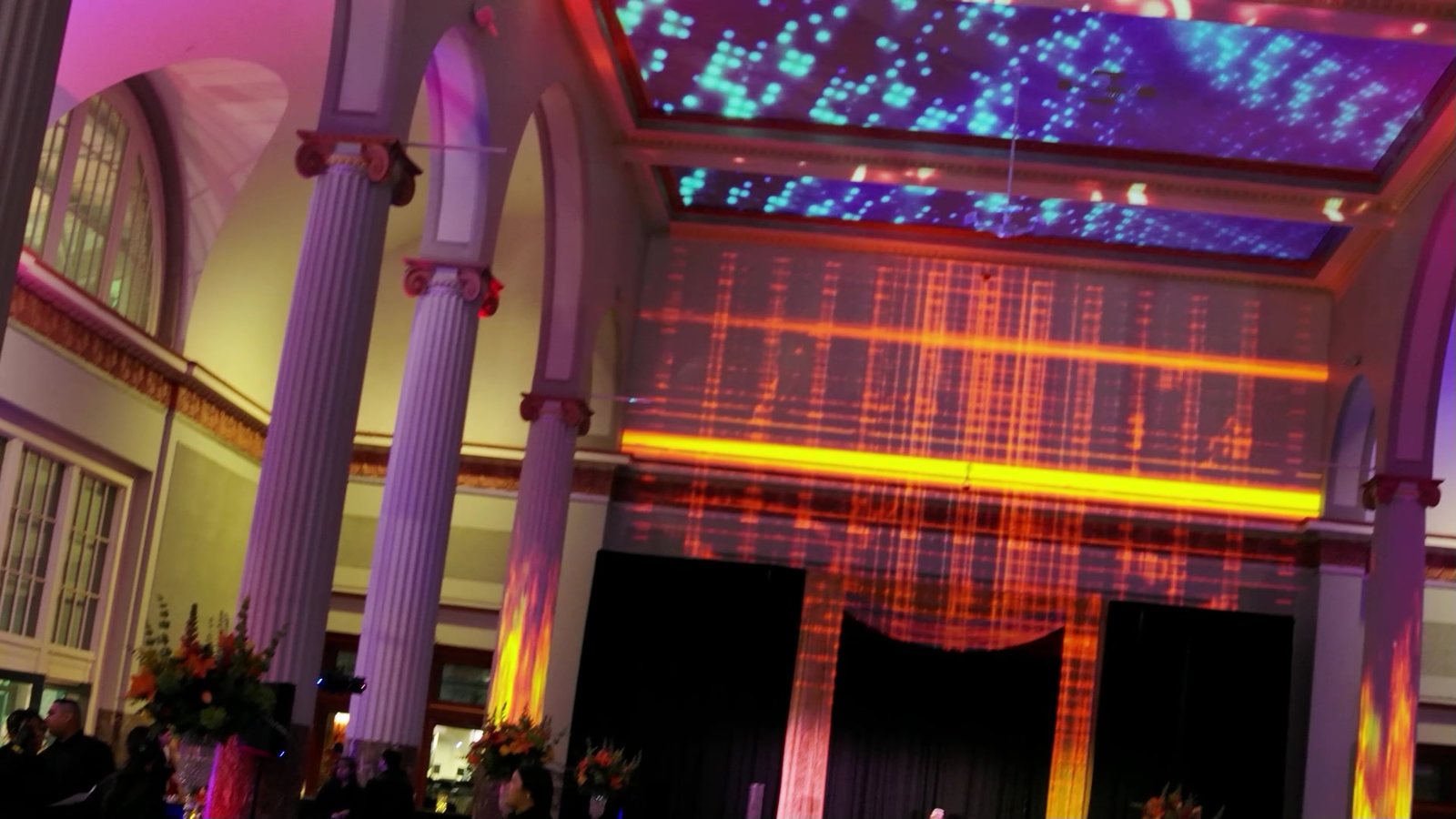 Separate projection-mapped content on each surface at Historic Union Station: cyan particles on the ceiling bays, an orange grid on the back wall and flame textures on the columns